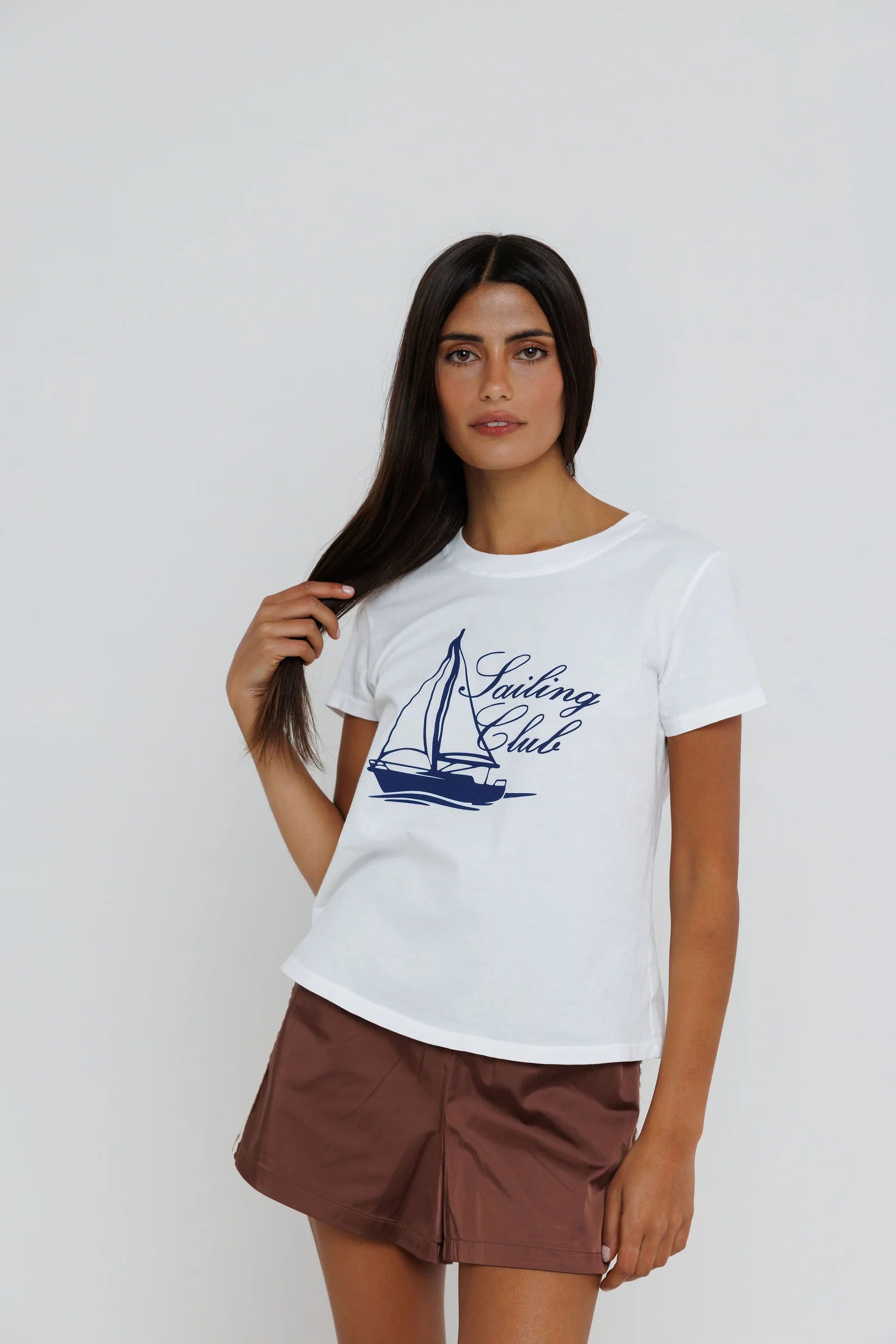 Woman wearing a white t-shirt with a sailboat graphic and 'Sailing Club' text on a plain background
