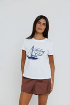 Woman wearing a white t-shirt with a sailboat graphic and 'Sailing Club' text on a plain background