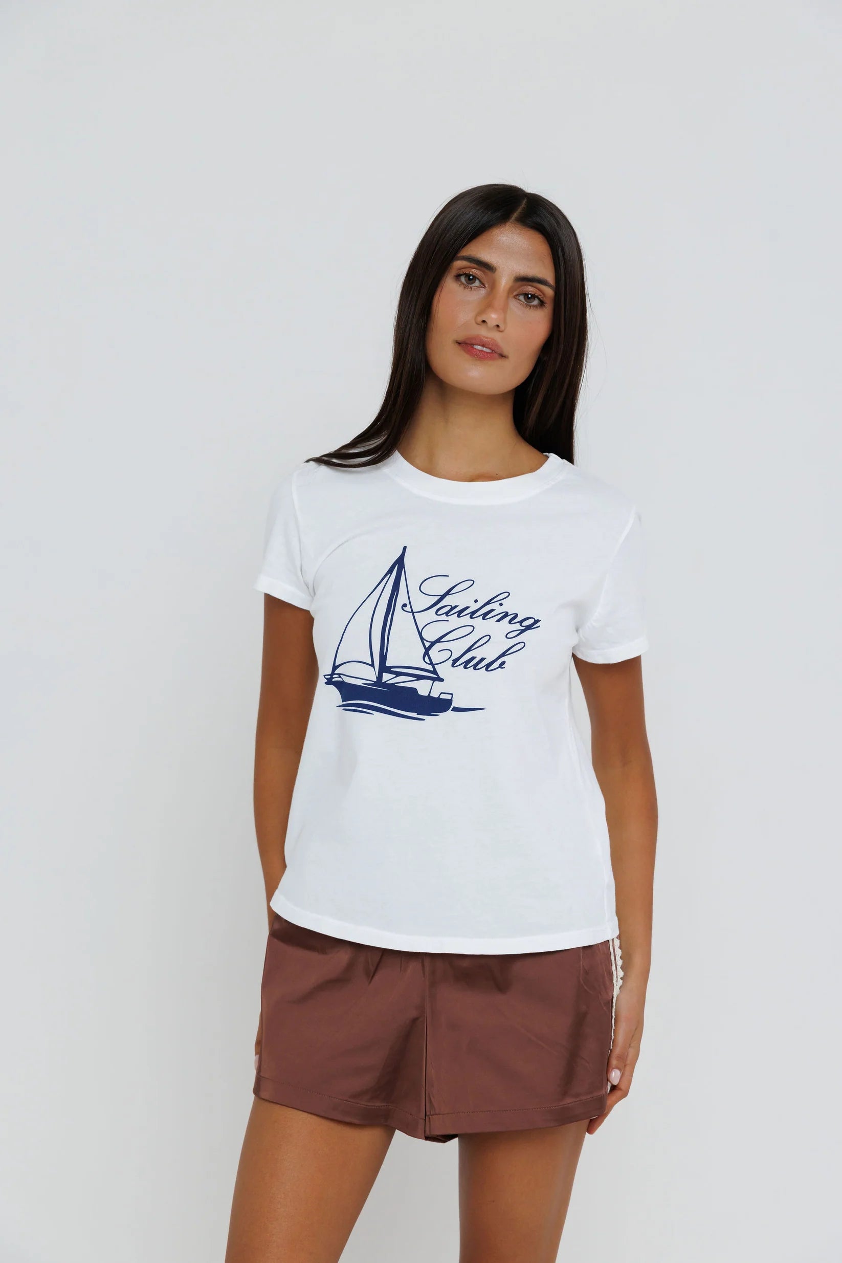 Woman wearing a white t-shirt with a sailboat graphic and 'Sailing Club' text on a plain background