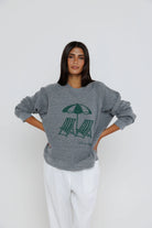 Woman wearing a gray sweatshirt with a graphic design on a white background