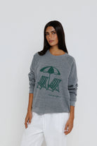 Woman wearing a gray sweater with a graphic design on a white background