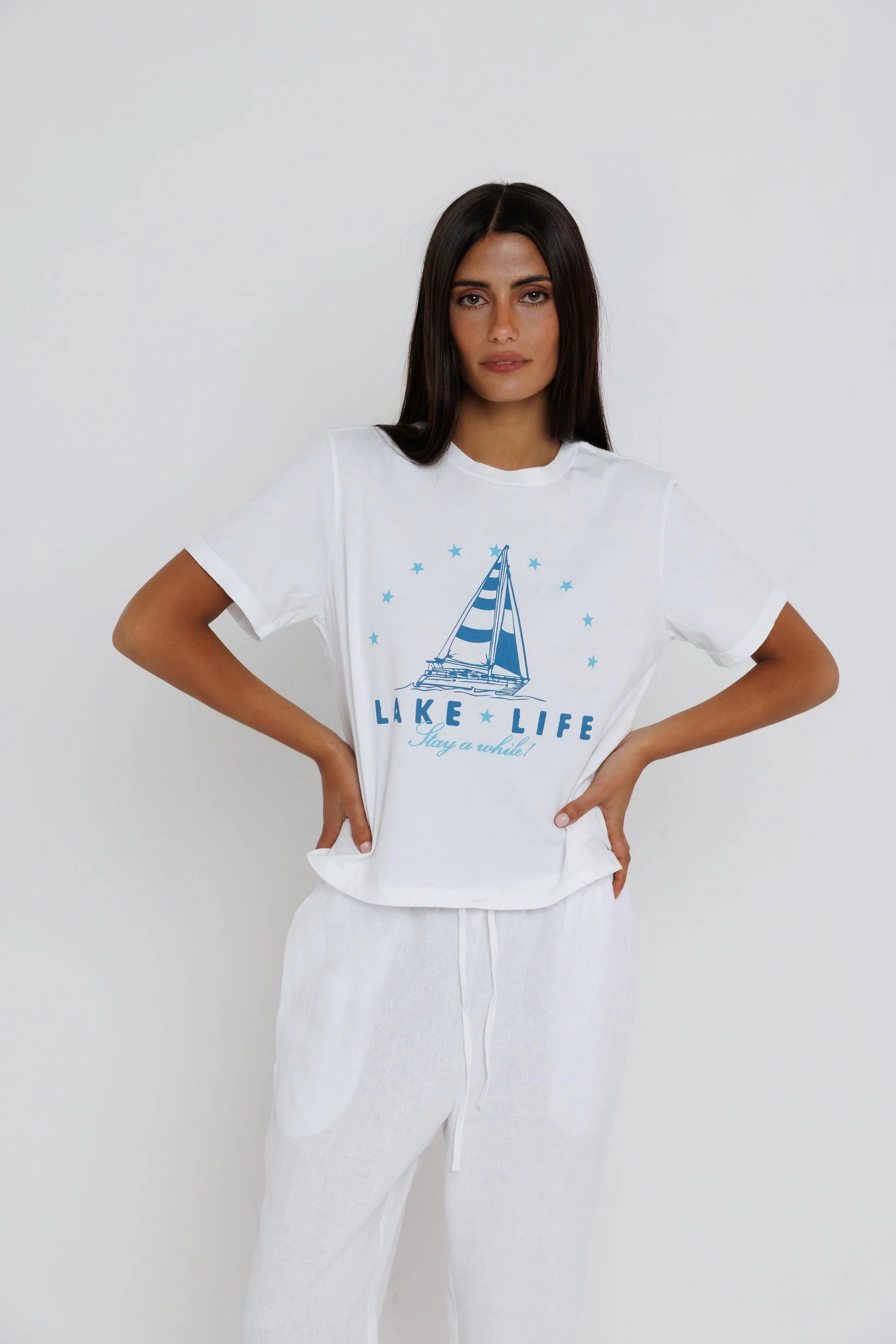 Woman wearing a white t-shirt with a graphic design and text on a plain background