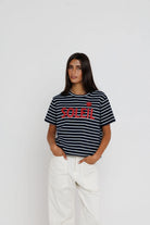 Woman wearing a black and white striped t-shirt with red text on a plain background