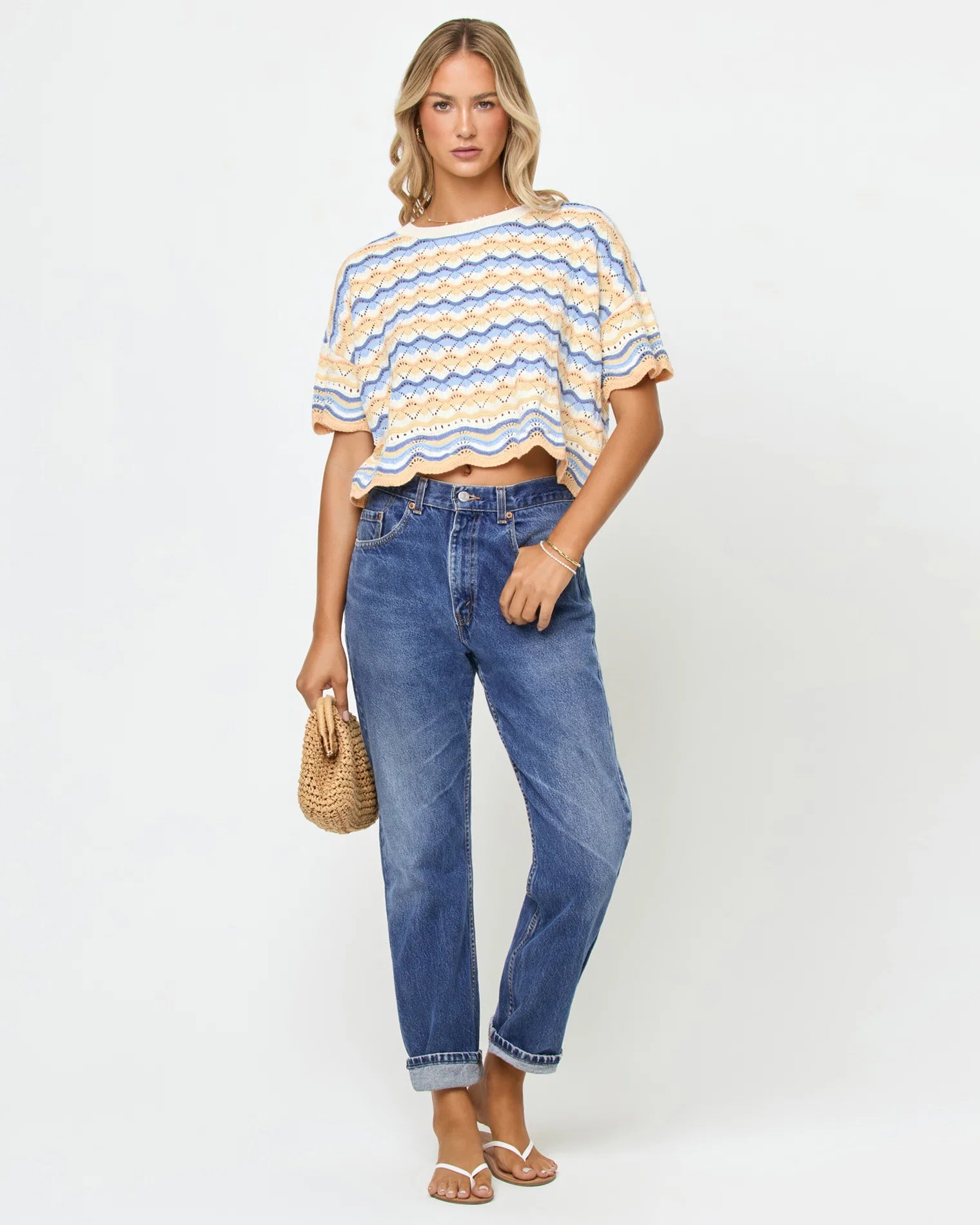 Woman wearing a striped shirt and blue jeans against a white background