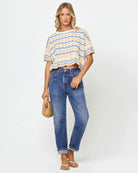 Woman wearing a striped shirt and blue jeans against a white background