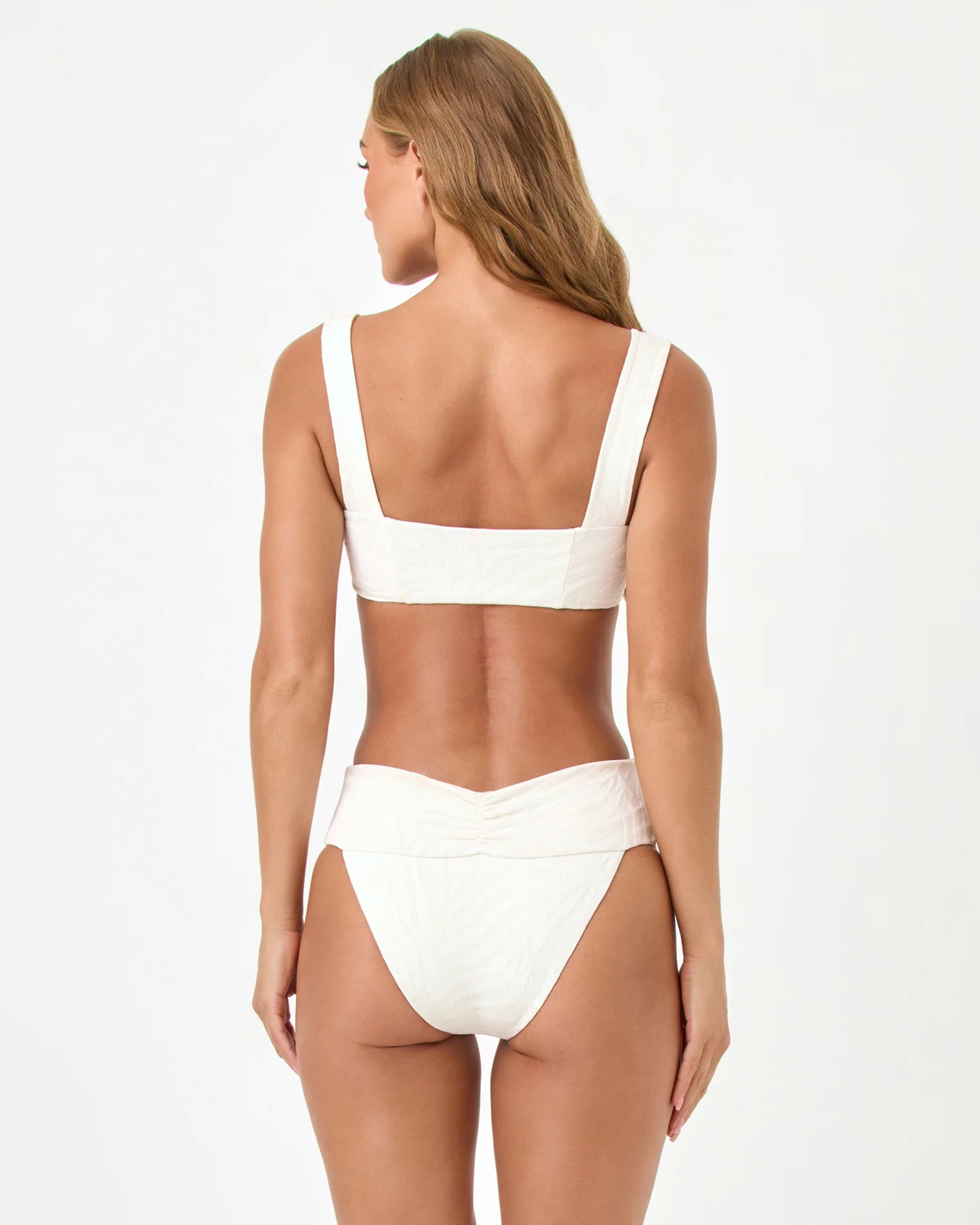 Woman wearing a white bikini on a plain background