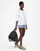 Woman holding a black backpack against a white background