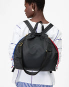 Person wearing a black backpack with colorful straps on a white background