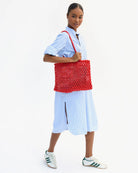 Person holding a red woven bag against a white background
