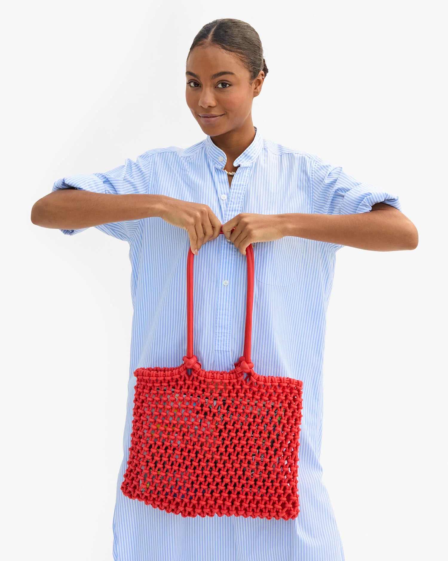 Woman holding a red woven handbag against a white background