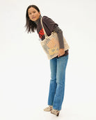 Woman holding a woven bag against a white background