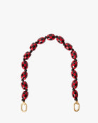 Red and black beaded bag strap with gold hardware on a white background
