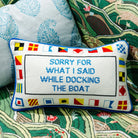 Decorative pillow with nautical-themed text and flags on a patterned fabric background