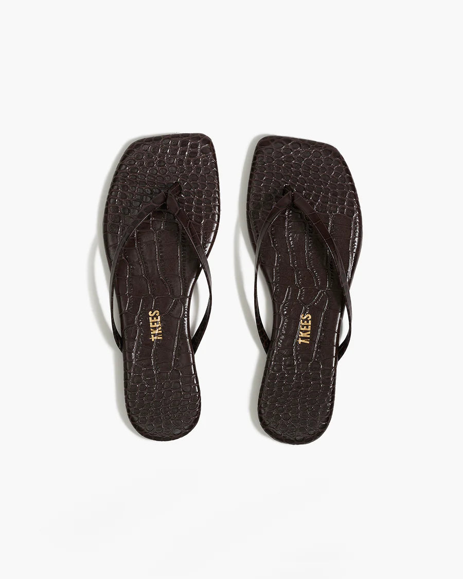 Pair of black flip-flops with 'TREES' branding on a white background