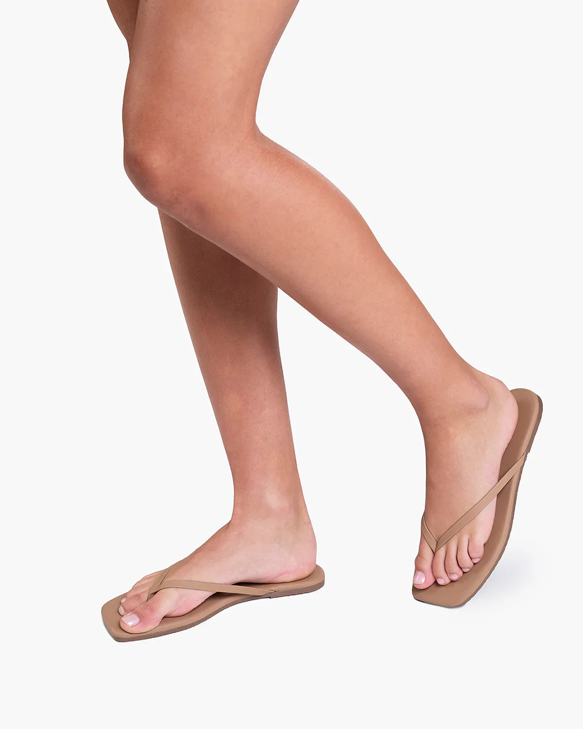 Person wearing beige flip-flops on a white background