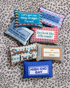 Collection of colorful pillows with humorous text on a patterned surface