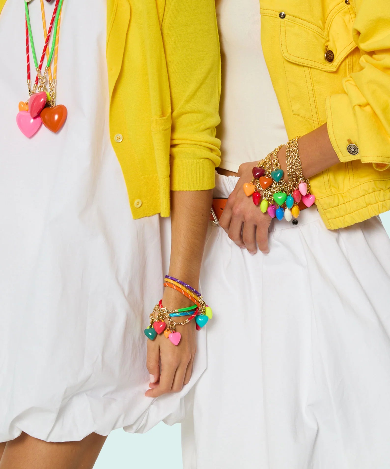 Person wearing colorful bracelets and a yellow jacket on a white background