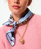 Person wearing a colorful scarf and gold necklace with a heart pendant.