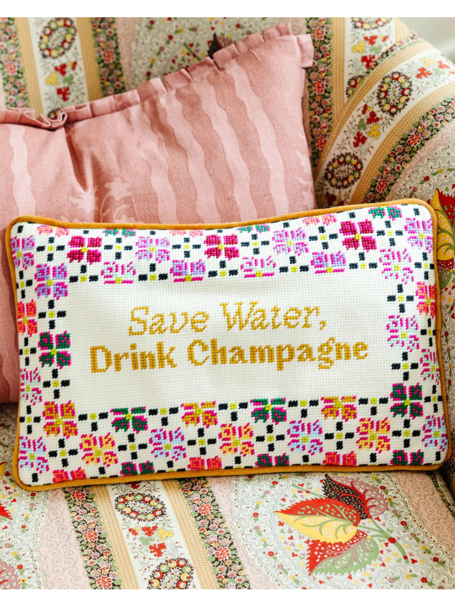 Embroidered pillow with 'Save Water, Drink Champagne' text on a floral background