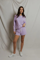 Woman wearing a lavender tracksuit against a plain background