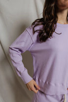 Person wearing a lavender sweatshirt against a plain background