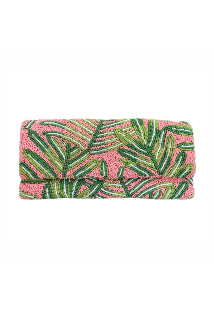 Pink clutch with green leaf pattern on a white background