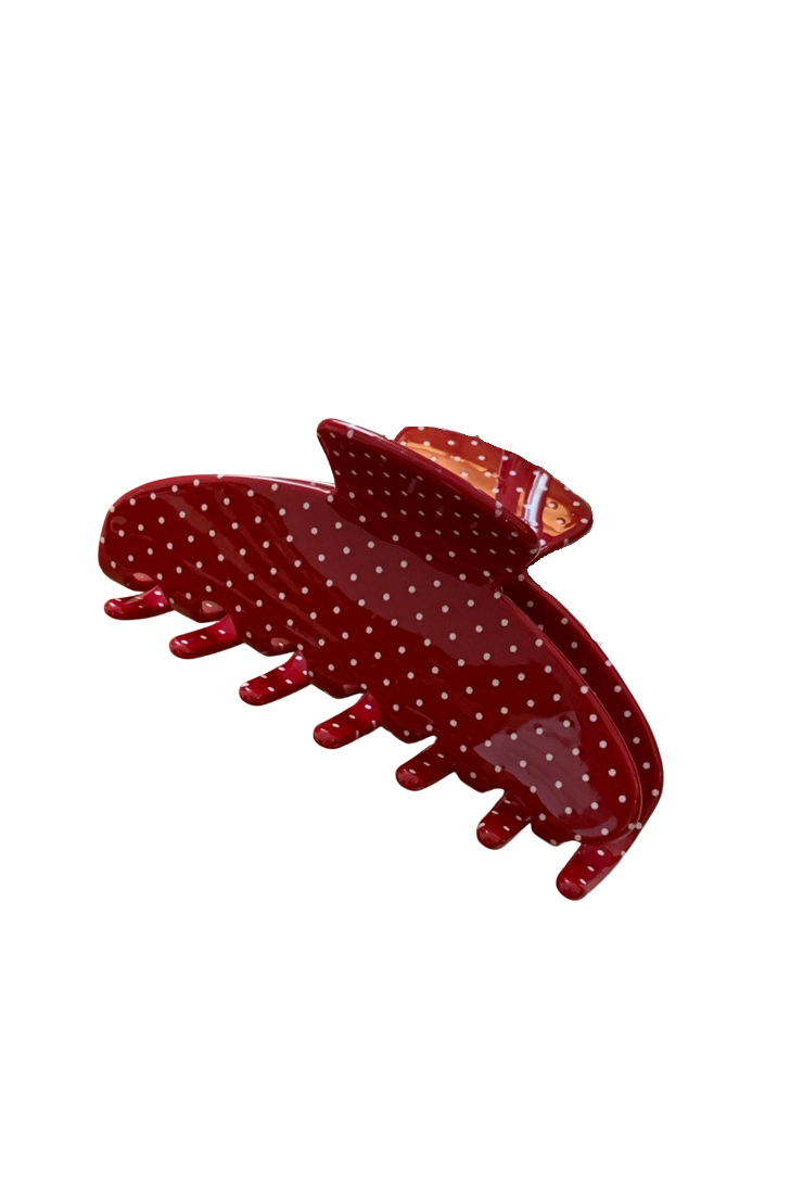 A glossy red hair claw clip with white polka dots, shown on a plain white background.