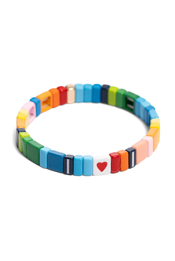 A colorful beaded stretch bracelet made of small rectangular beads in rainbow colors, with a white bead featuring a red heart in the center, shown on a plain white background.