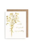 A white sympathy greeting card with gold foil wildflower illustrations and the words 'with deepest sympathy' in gold script, shown with a brown kraft envelope behind it on a white background.