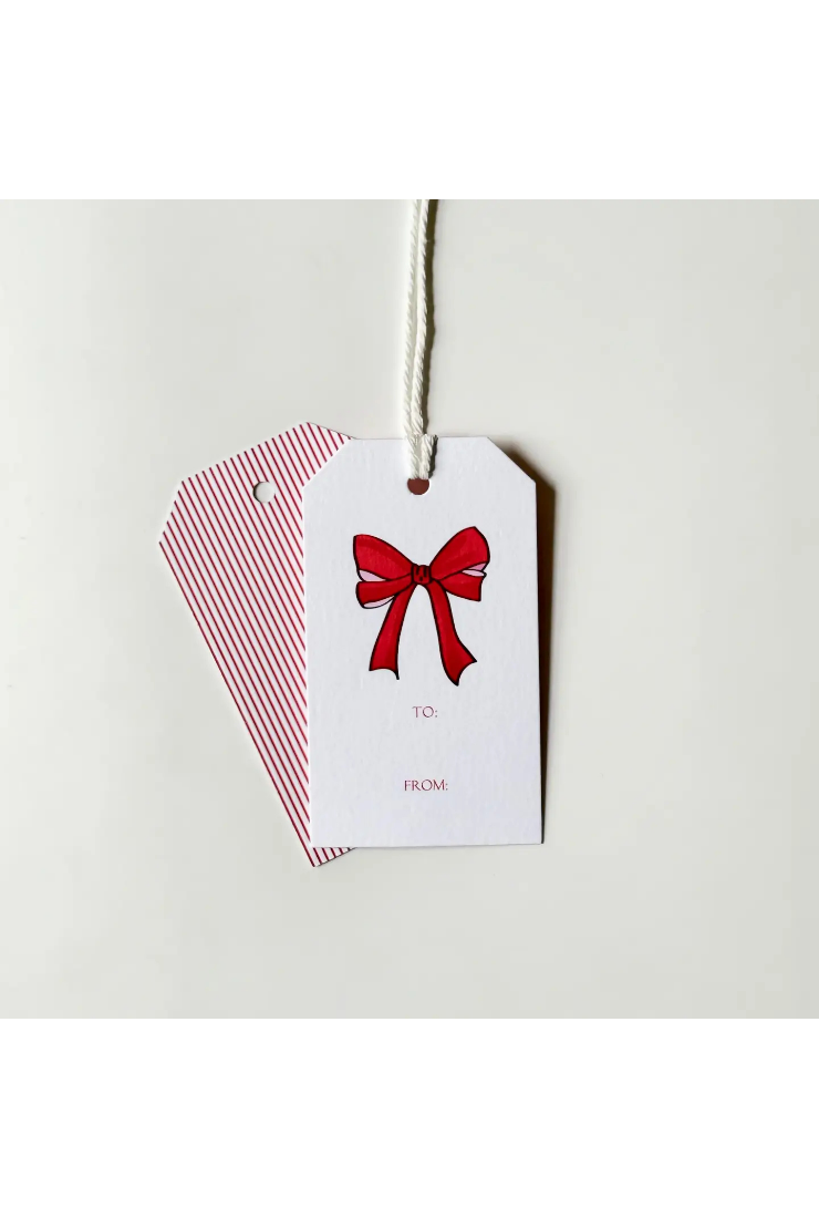 Two gift tags on a white string against a light gray background. The front tag is white with a red bow illustration and small 'TO' and 'FROM' text, while the back tag has thin red vertical stripes on a white background.