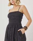 Woman wearing a black dress with thin straps on a plain background