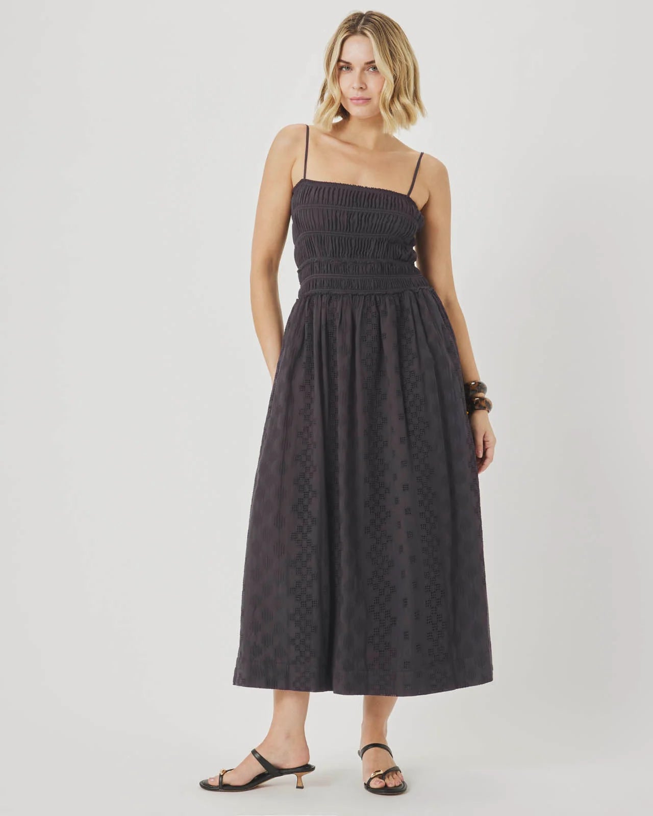 Woman wearing a dark patterned dress on a plain background