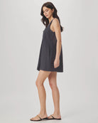 Woman wearing a dark gray slip dress on a plain background