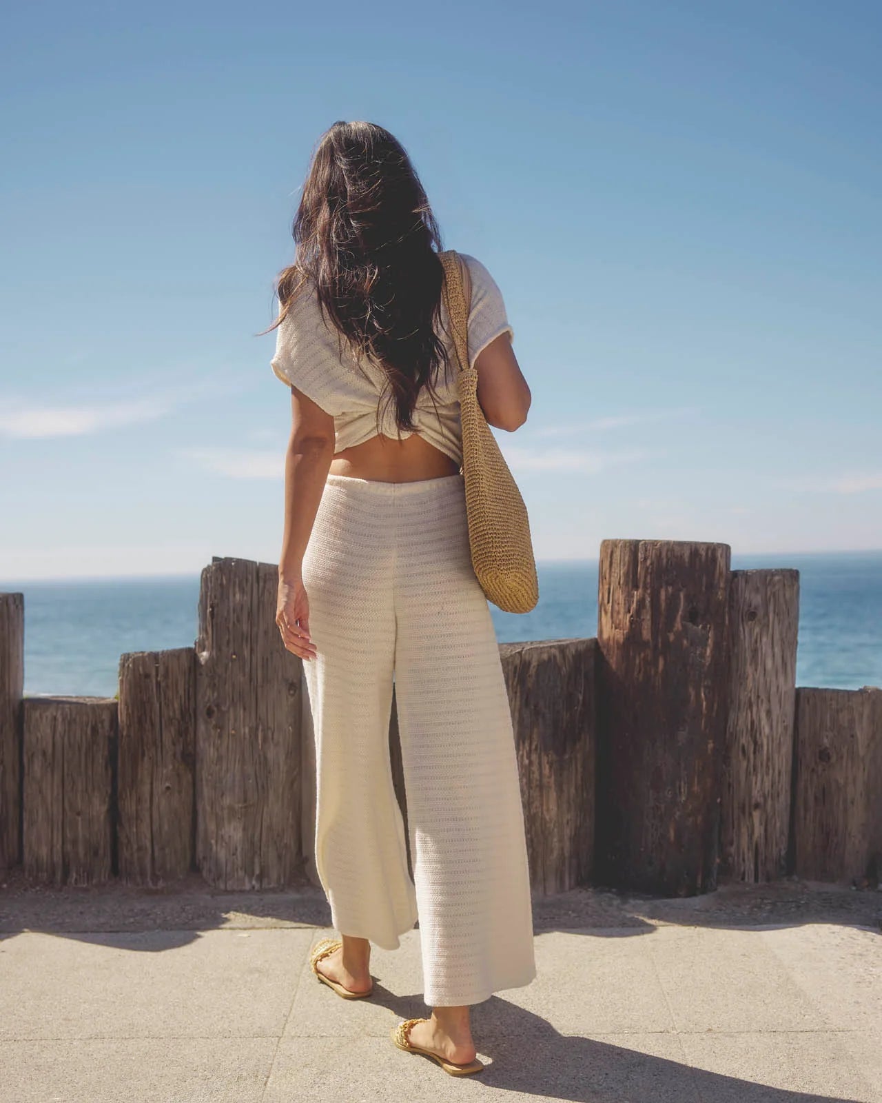 Woman standing by a wooden barrier with ocean view