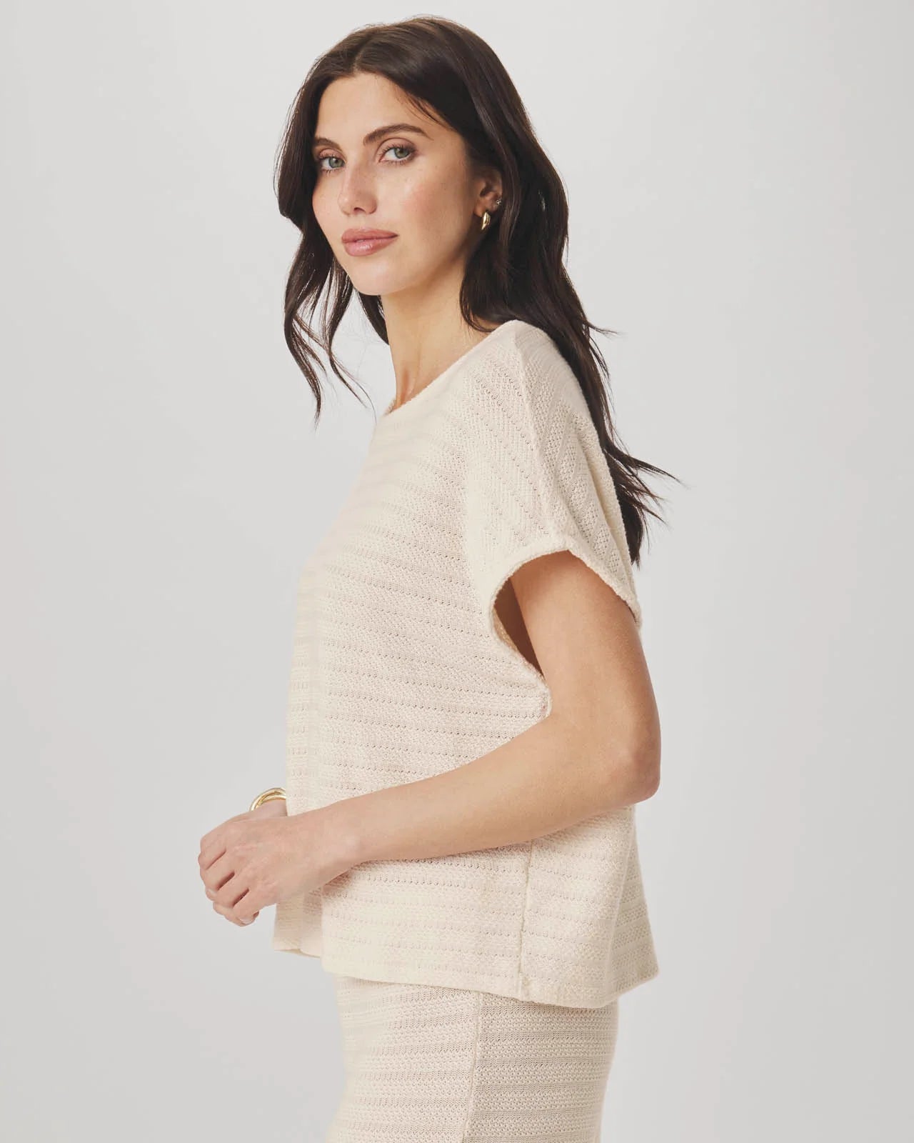 Woman wearing a beige knit outfit on a plain background