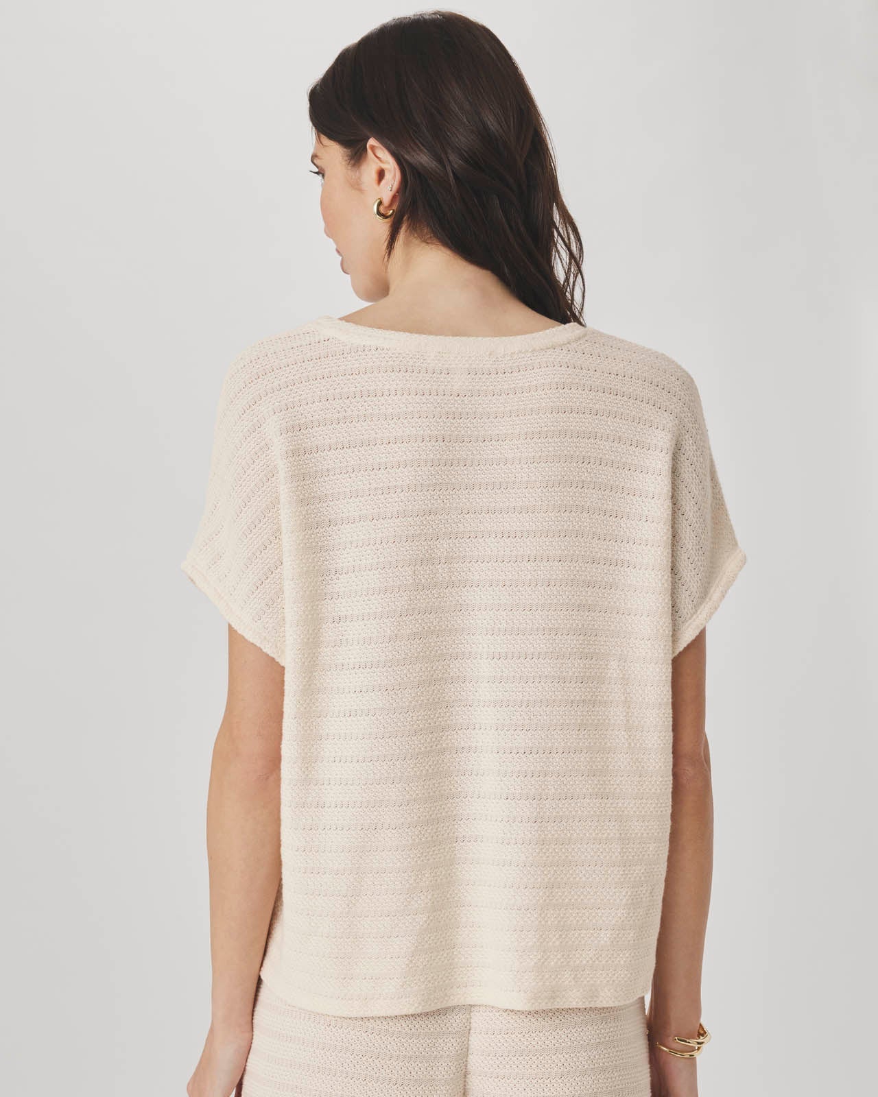 Woman wearing a beige knit top against a plain background