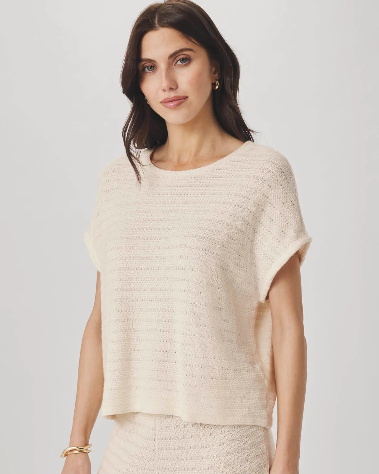 Woman wearing a beige knit top against a plain background