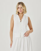 Woman wearing a white sleeveless dress against a plain background