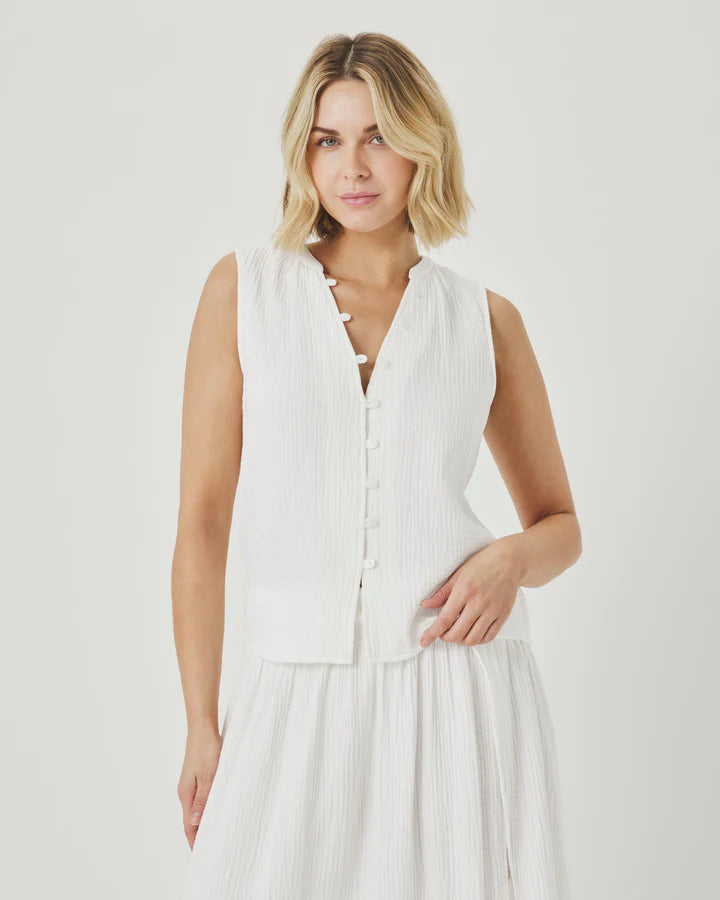 Woman wearing a white sleeveless dress against a plain background
