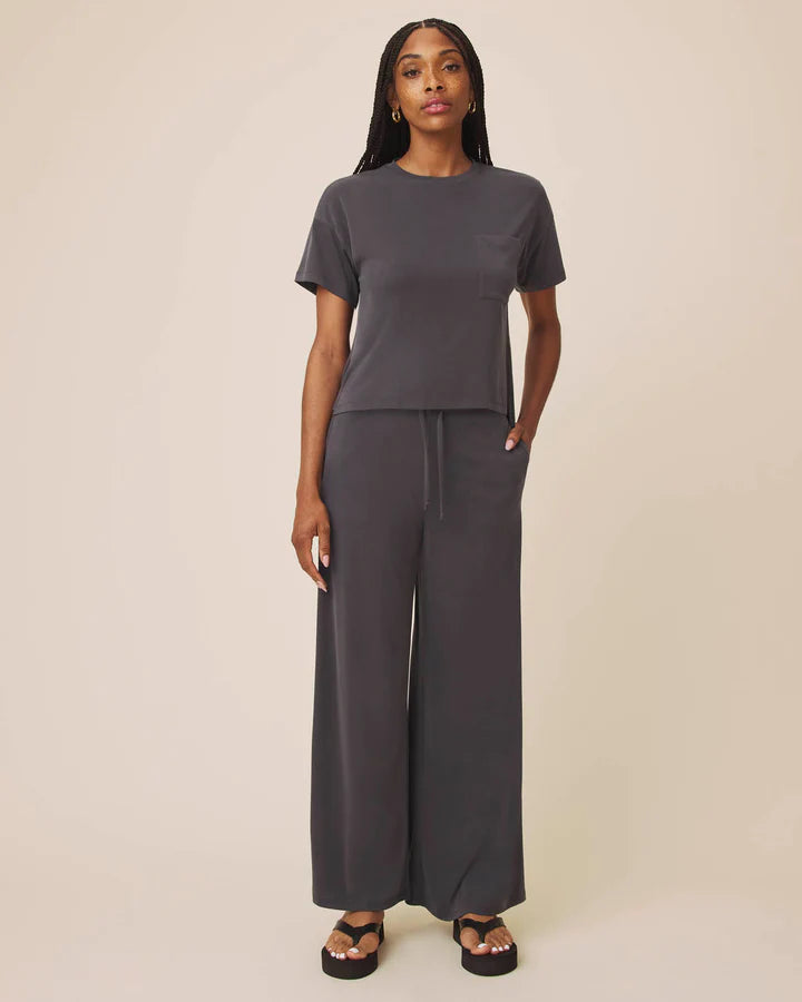 Woman wearing a gray outfit with wide-leg pants on a beige background