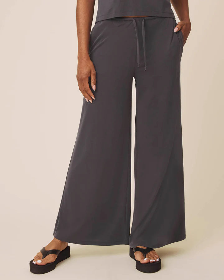 Person wearing dark gray wide-leg pants on a plain background