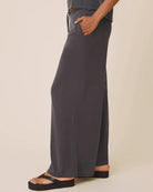 Person wearing dark gray wide-leg pants on a beige background