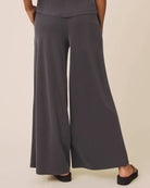Person wearing dark gray wide-leg pants on a beige background