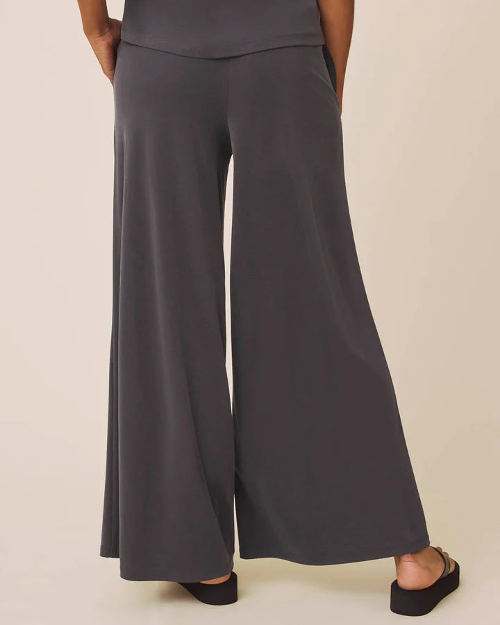Person wearing dark gray wide-leg pants on a beige background