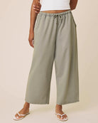 Person wearing light green wide-leg pants on a beige background