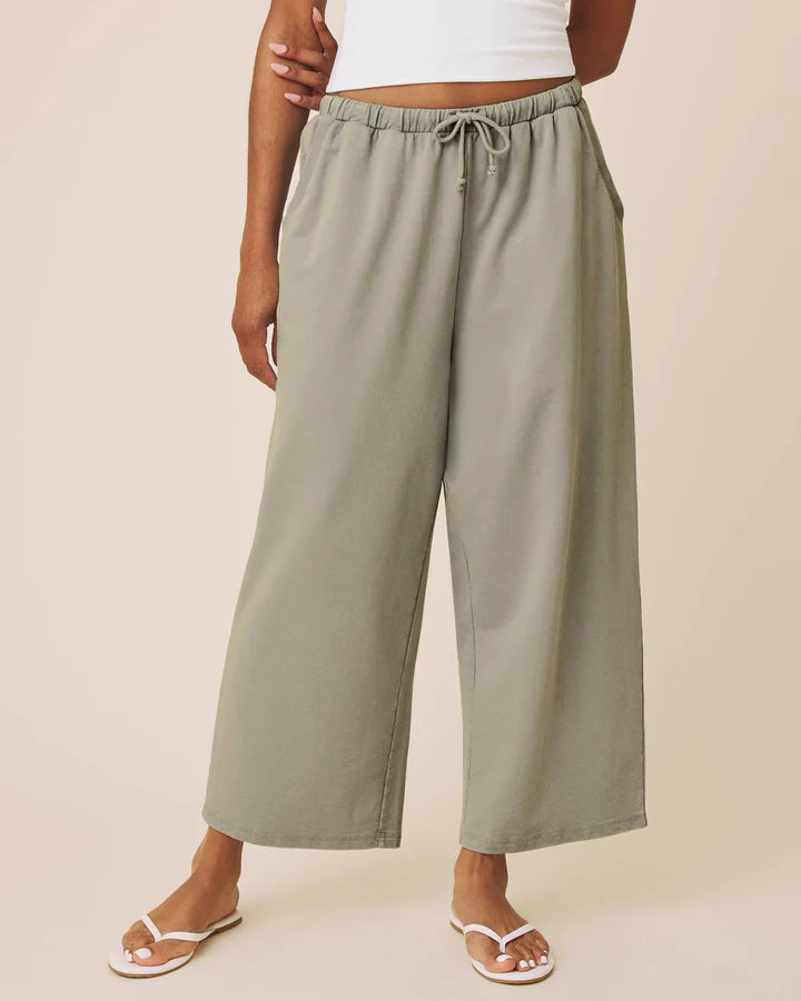 Person wearing light green wide-leg pants on a beige background