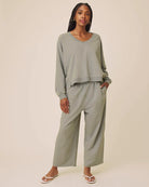 Woman wearing a matching green outfit with wide-leg pants on a beige background