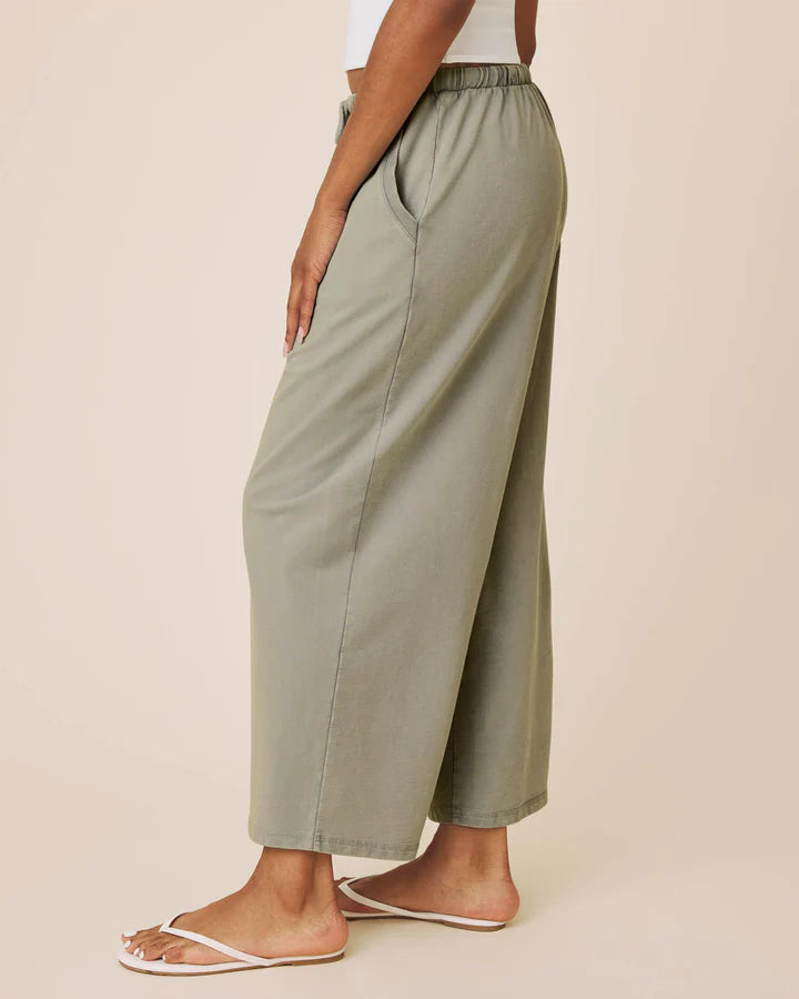 Person wearing olive green wide-leg pants on a beige background