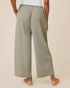Person wearing light green wide-leg pants on a beige background