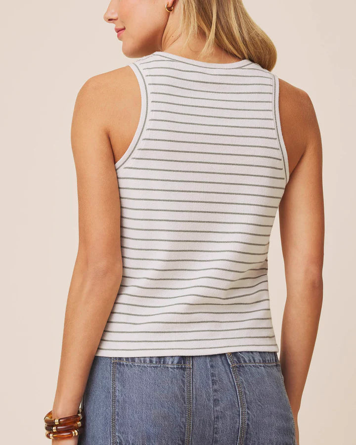 Woman wearing a striped tank top and jeans on a beige background